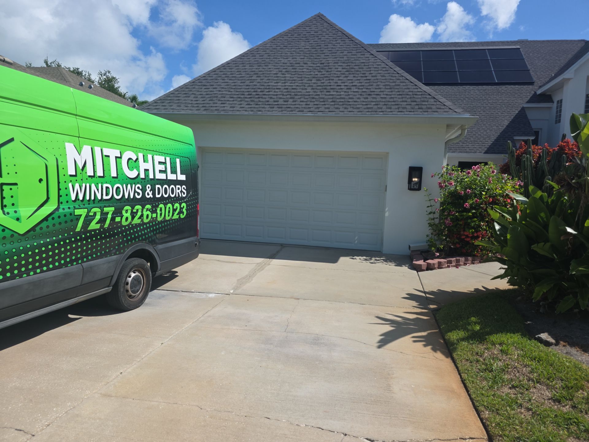 A Mitchell Windows and Doors service van parked in the driveway of a single-story Florida home on a clear day